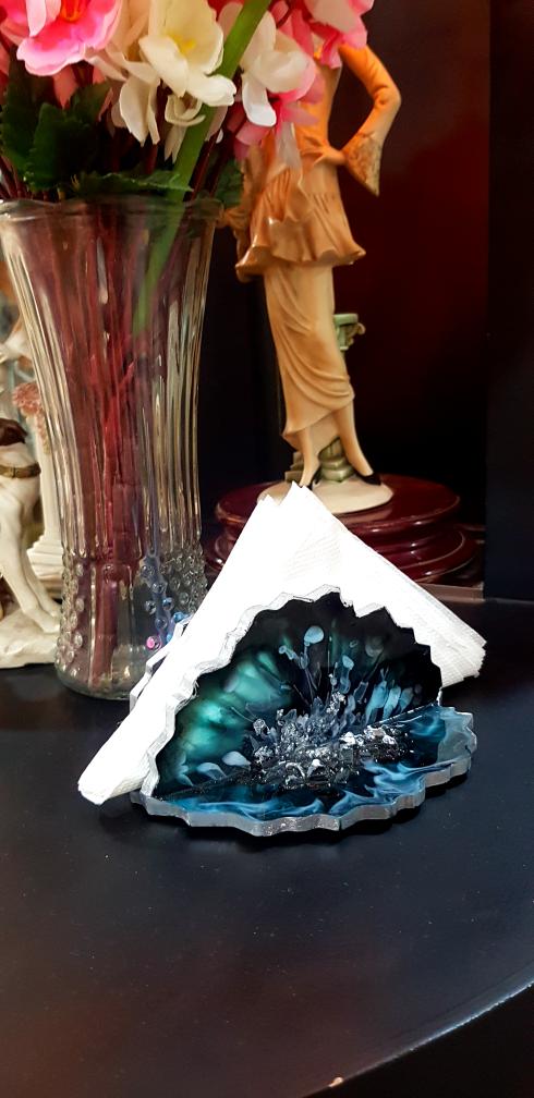 Decorative blue crystal on a white base with a vase of flowers and figurine in the background.