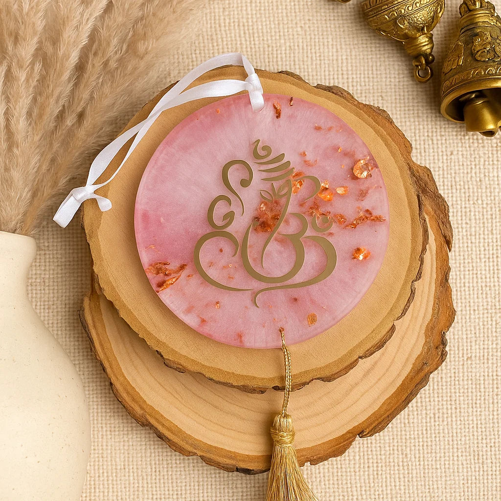 Decorative item with Om symbol on a pink background, placed on a wooden surface.