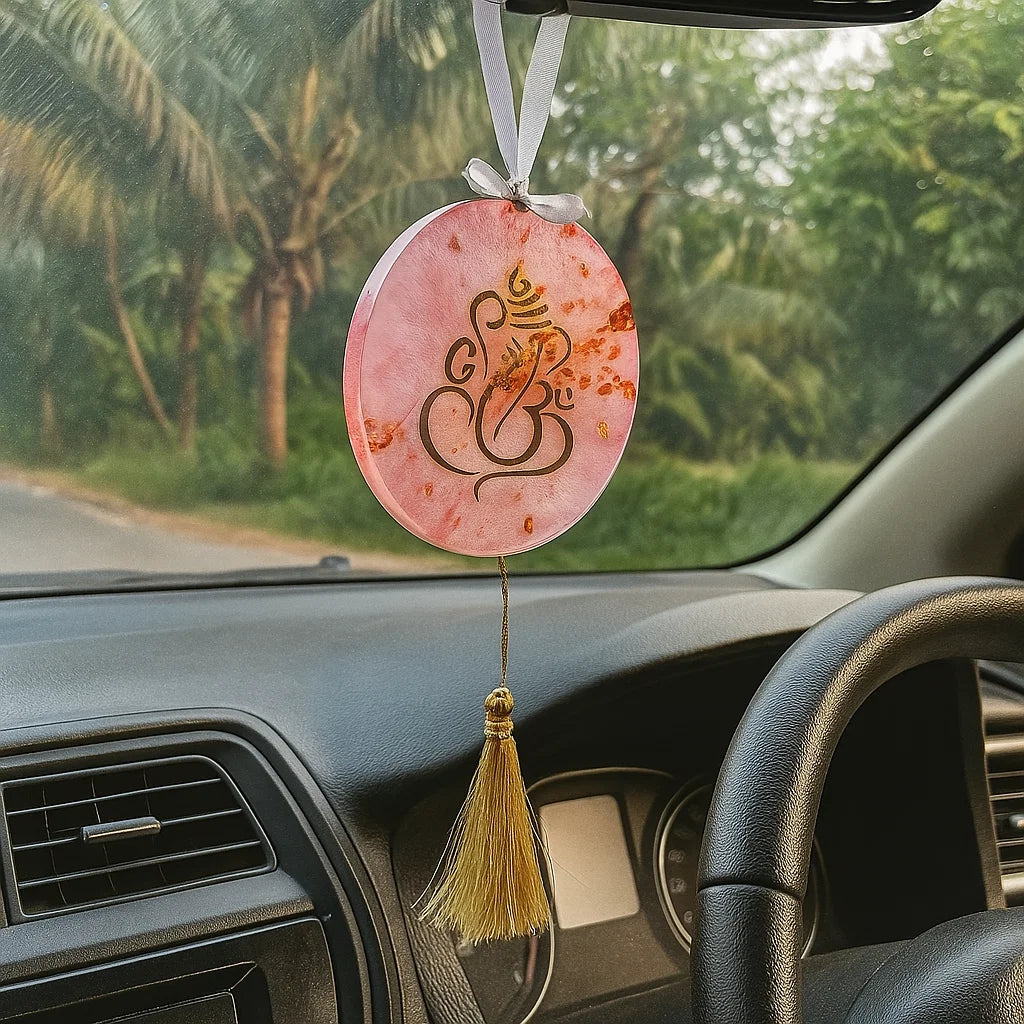 Decorative car hanging with a pink circular design and tassel inside a car.