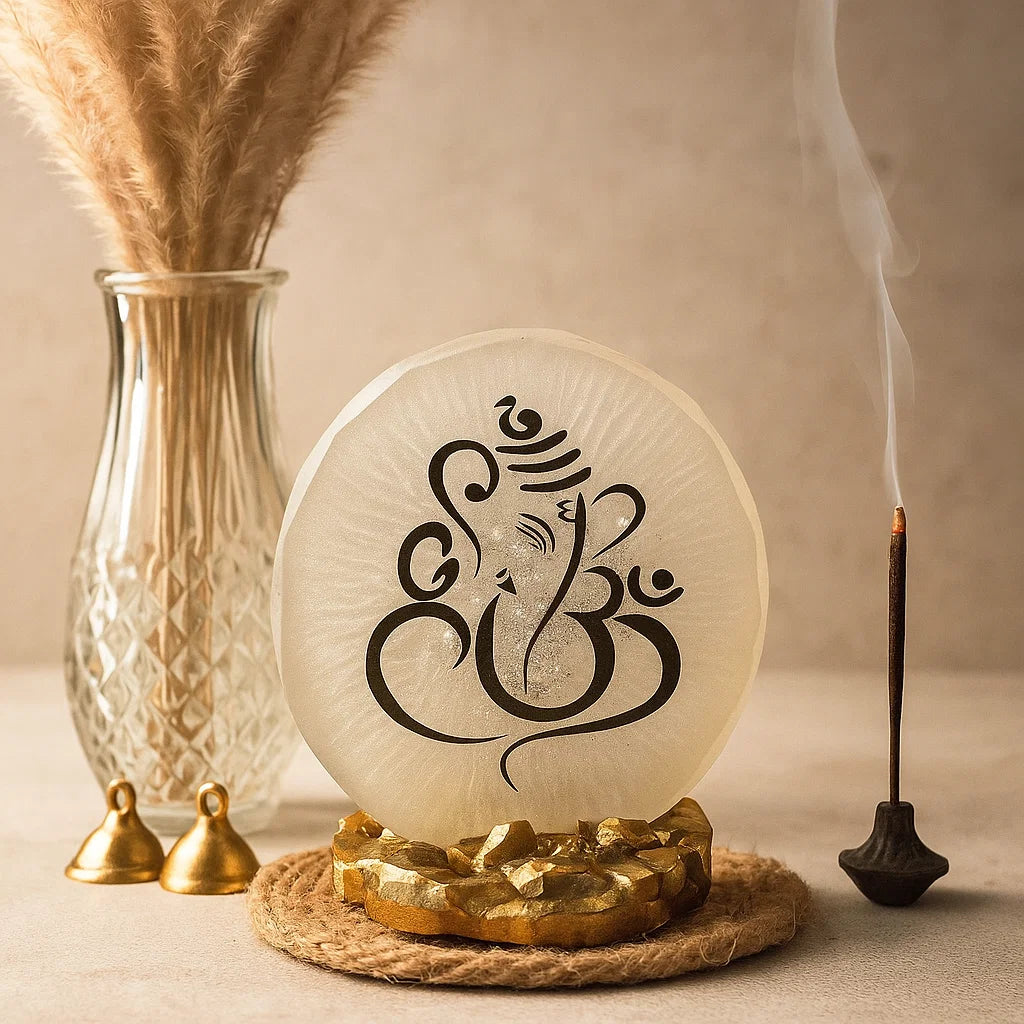 Decorative item with Ganesha symbol on a round white stone, surrounded by gold elements and a vase with dried plants.