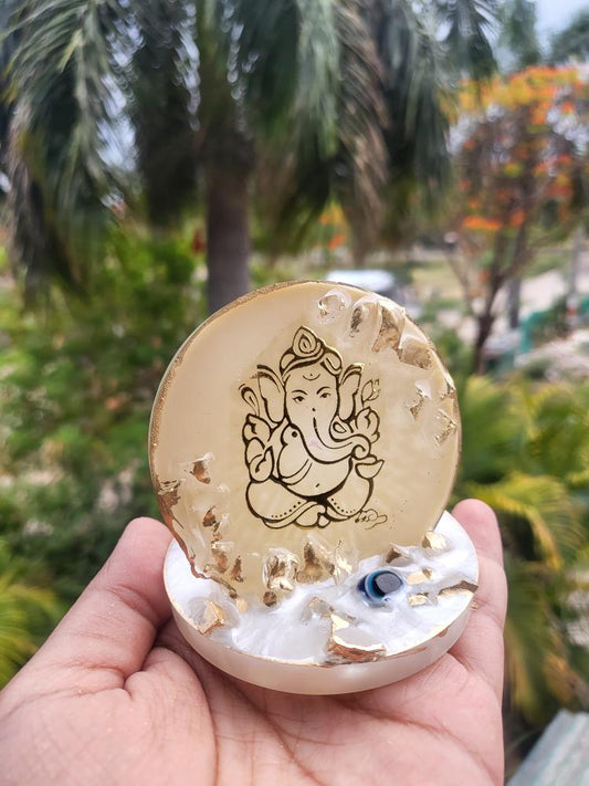 A ganesha Stand held by a hand in lush green surrounding