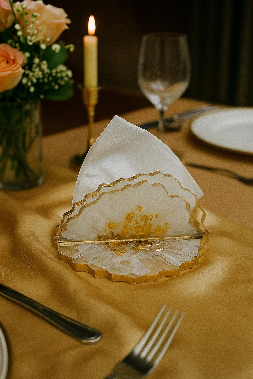 Decorative table setting with a napkin holder, white napkin, and floral arrangement on a yellow tablecloth.