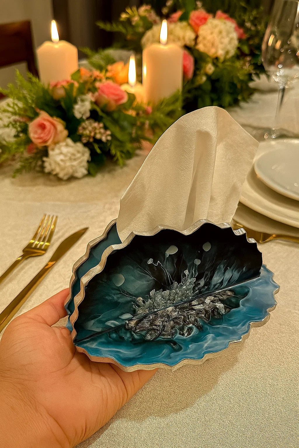 Resin tissue holder in a dark blue hue held by a hand in an elegant dining setup