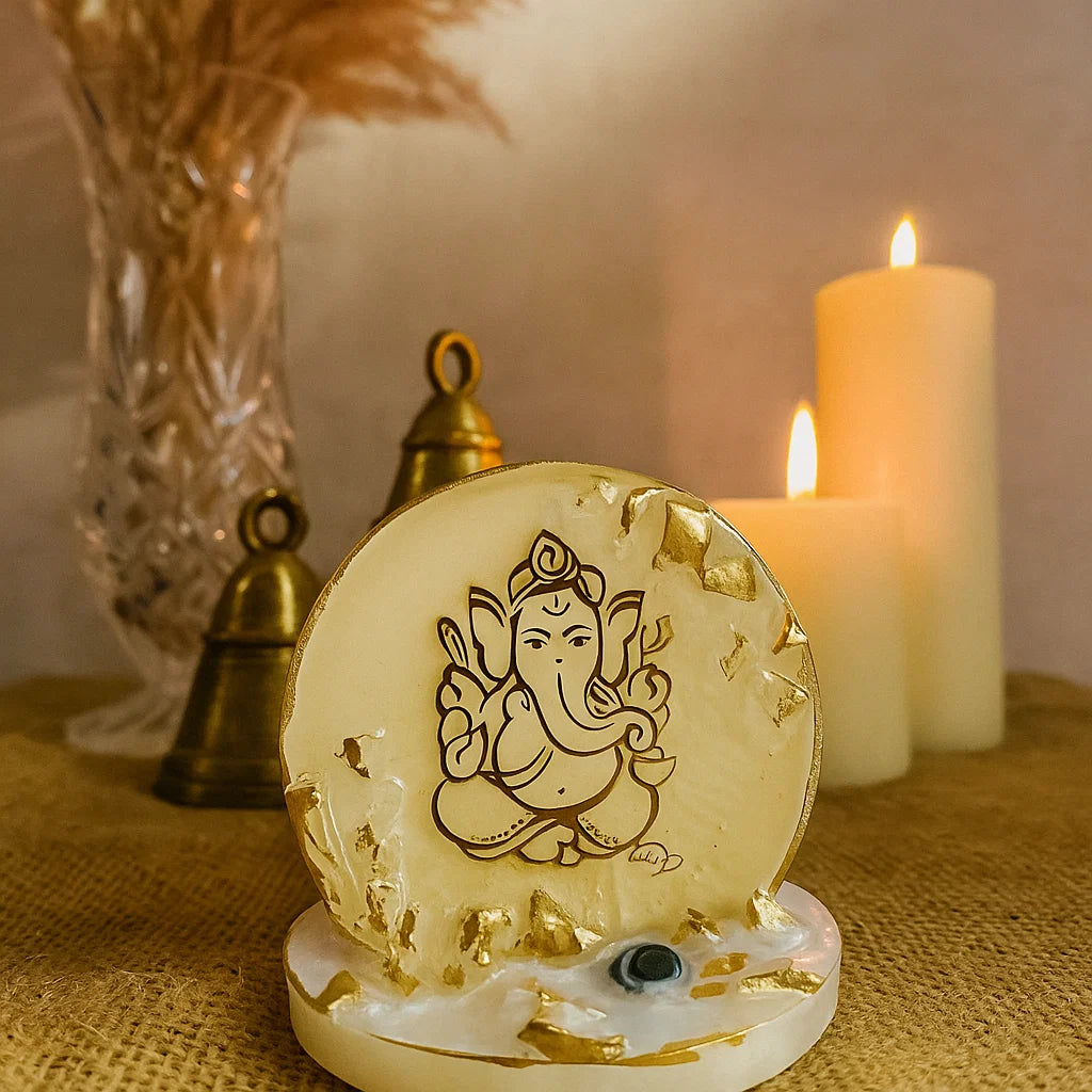 A Ganesha Figurine in a temple setting with metal bells and lit candles 